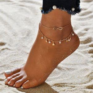 Anchored foot with gold anklets on a sandy background