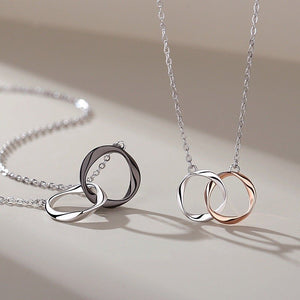 Two necklaces with interlocking rings on a beige background