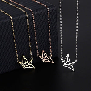 Three necklaces with origami crane pendants on a black background