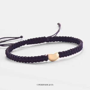 Navy braided bracelet with a gold heart-shaped clasp on a light gray background