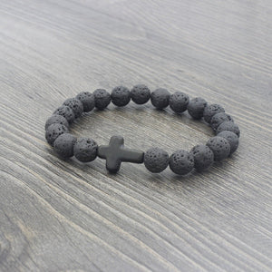 Black beaded bracelet with a cross charm on a wooden surface