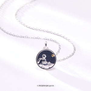 A sterling silver necklace with a round pendant featuring a fox and a star on a moonlit background. The pendant is gold plated, and the necklace is adjustable.