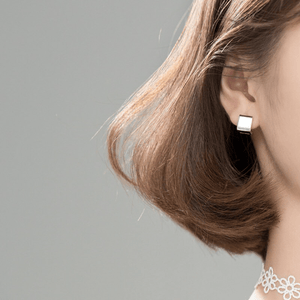 Model wearing square hoop earrings on a light gray background