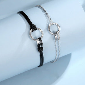 Silver bracelet with black cord and silver chain on a light blue background