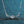 Silver necklace with a diamond on a blue textured background