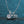 Silver bicycle-shaped necklace with a clear gemstone on a blue textured background