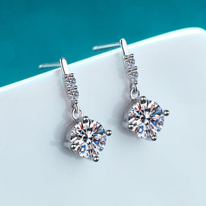 Silver earrings with large gemstones on a white surface with a teal background