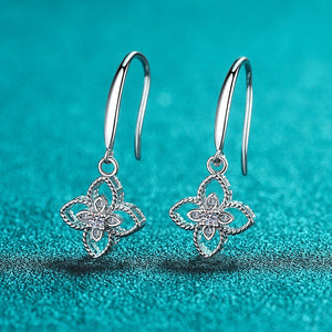 Silver floral earrings on a teal fabric background