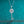 Silver key-shaped pendant necklace with a diamond on a teal background