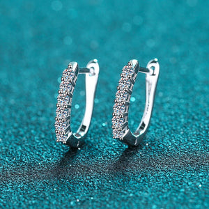 Silver hoop earrings with embedded stones on a teal textured background
