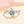 Silver ring with a large diamond and smaller diamonds on the band against a soft pink background