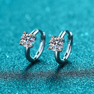 Pair of silver hoop earrings with gemstones on a blue textured background