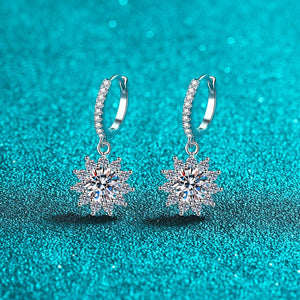 Silver earrings with star-shaped gemstones on a turquoise glitter background