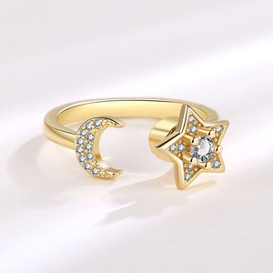 Gold spinner ring with star and moon design on a white background
