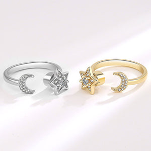 Silver and gold spinner ring with star and moon design on a white background