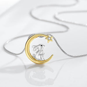 Jewelry pendant with a rabbit on a gold crescent moon and star against a white background