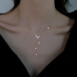 Necklace with star and moon pendant on a person wearing a black top