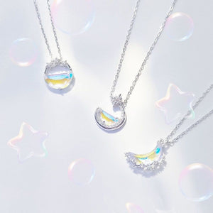Three moon-shaped necklaces with colorful accents on a light gray background