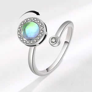 A silver-colored fidget spinner ring with a central moonstone gem surrounded by smaller cubic zirconia stones, with a sleek and adjustable band.