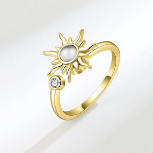 Gold ring with sun design and opal center on a light gray background