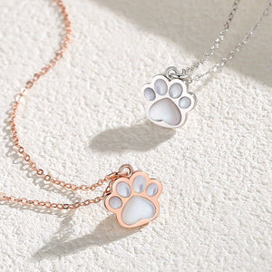 Two paw-shaped pendants on rose gold and silver chains on a textured white surface.