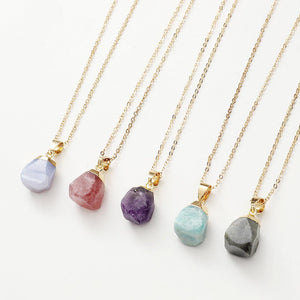 Five gold necklaces with colorful stone pendants on a white background