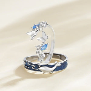 Silver ring with blue accents and butterfly design on a beige background