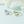Gold and silver leaf-shaped rings on a light blue background with white fabric.