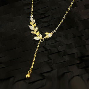 Gold necklace with leaf design on a black background