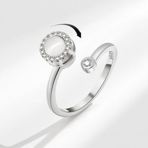 An adjustable silver-colored fidget spinner ring with a central opal stone and small cubic zirconia accents.
