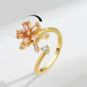 Gold ring with floral design and gemstones on a light gray background