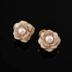 Pair of floral earrings with pearls and gold accents on a black background