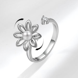 Silver ring with a flower design and a pearl on a light gray background