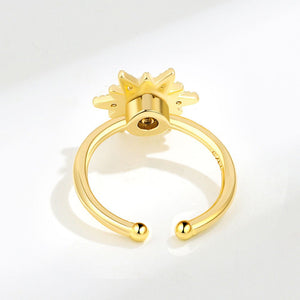 An adjustable spinner ring with a sun motif, featuring a pearl at the center, surrounded by small cubic zirconia stones, with gold plating.