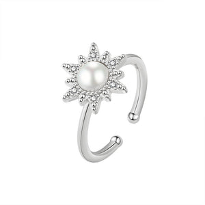 An adjustable spinner ring with a sun motif, featuring a pearl at the center, surrounded by small cubic zirconia stones, with gold plating.