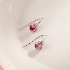 Silver earrings with pink floral charms on a light background
