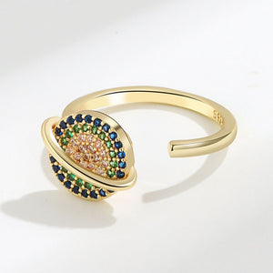 Gold spinner ring with saturn charm on a white background