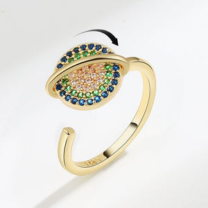 Gold spinner ring with saturn charm on a white background