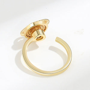 Gold spinner ring with saturn charm on a white background