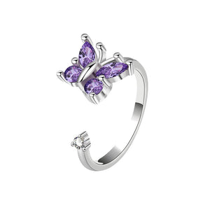 Silver spinner ring with purple gemstone butterfly design on a white background