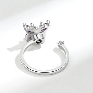 Silver spinner ring with purple gemstone butterfly design on a white background