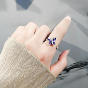 Model wearing a silver spinner ring with purple gemstone butterfly design on a white background
