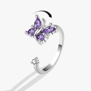 Silver spinner ring with purple gemstone butterfly design on a white background