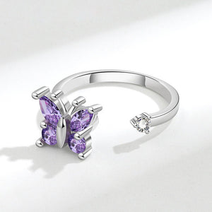 Silver spinner ring with purple gemstone butterfly design on a white background