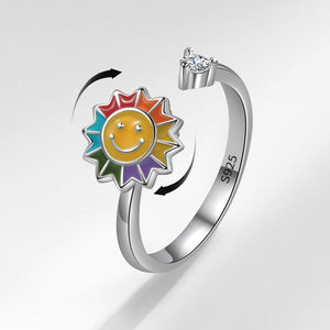 Silver ring with a colorful sun design and diamond on a light gray background