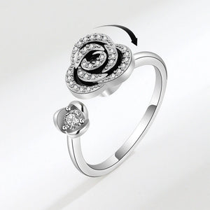 Silver ring with rose design and heart-shaped gem on a white background