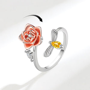 Two rings: one with a pink rose design and the other with a yellow gemstone, on a white background.