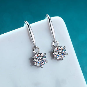 Silver earrings with clear gemstones on a white surface with a blue background