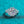 Silver ring with a large central gemstone on a teal background