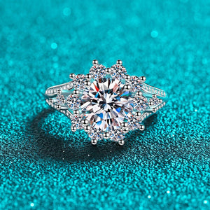 Silver ring with a large central gemstone on a teal background
